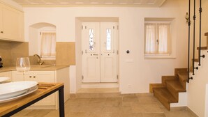 A kitchen with a dining table, a wine glass, and a double door leading to a staircase. - Il Sogno by Corfuescapes  (Corfu)