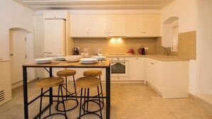 A kitchen with a central island, bar stools, a refrigerator, oven, and a sink. - Il Sogno by Corfuescapes  (Corfu)