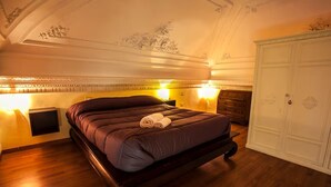 Ein Schlafzimmer mit einem großen Bett, Holzboden, dekorativer Decke und einem Kleiderschrank.
