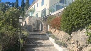 Escadaria de pedra que leva a um edifício com fachada branca e varanda de vidro.