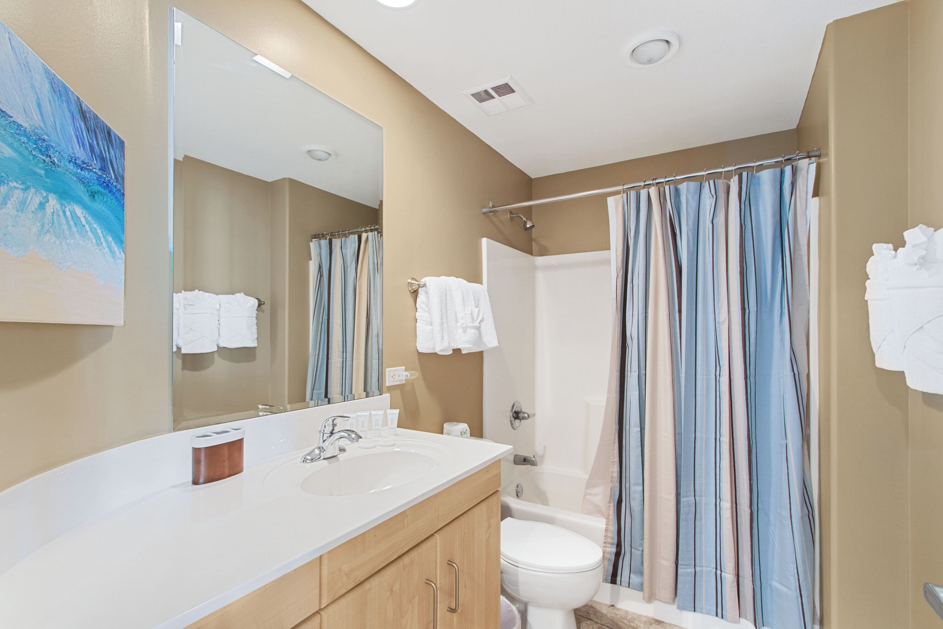 A bathroom with a white sink, a mirror, a shower curtain, and a toilet.