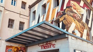Ein Gebäude mit einem Theaterschild und einem Wandgemälde an der Fassade.