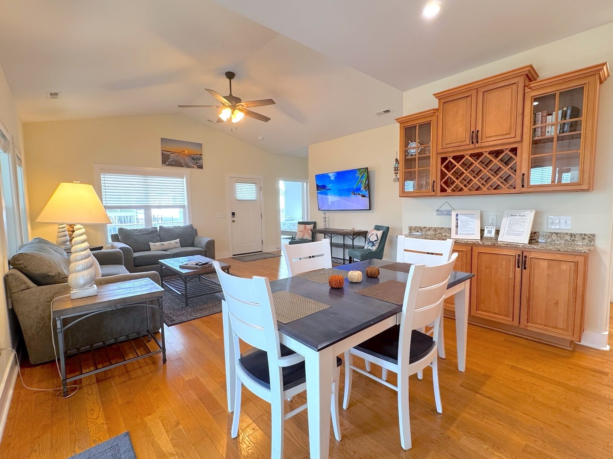 A spacious living area with a dining table, chairs, a sofa, and a television.