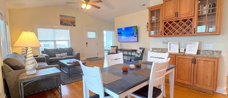 A spacious living area with a dining table, chairs, a sofa, and a television.