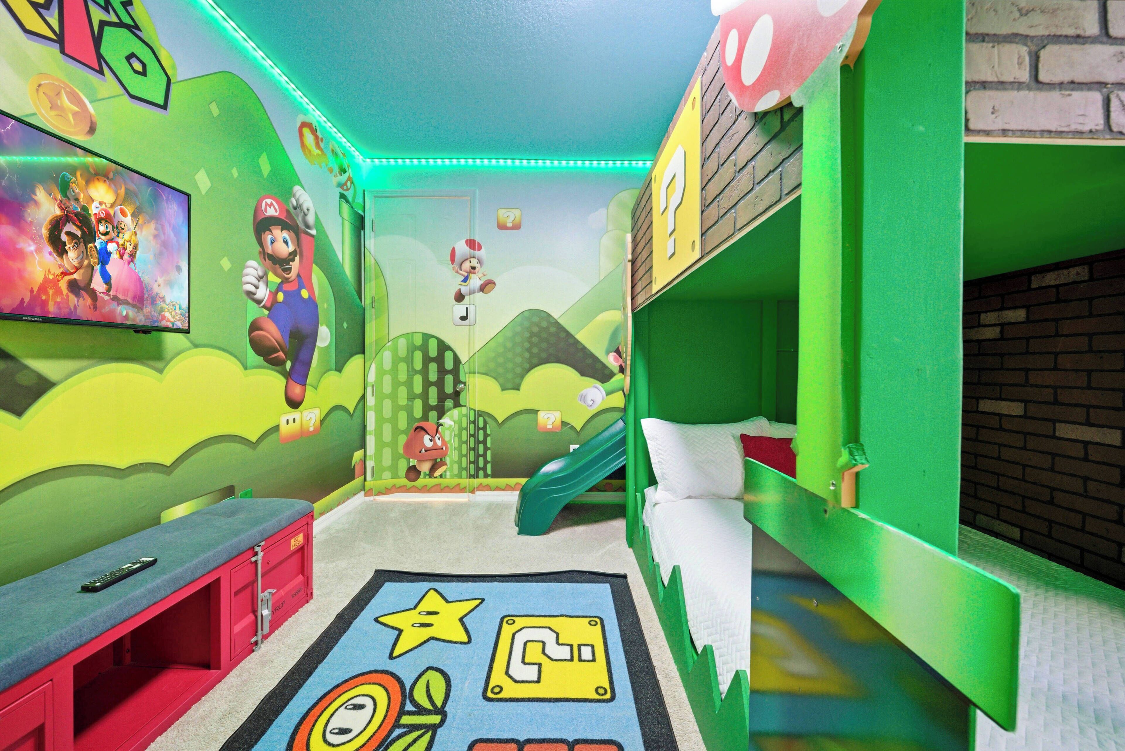 A children's playroom with green walls, a TV, bunk beds, and a slide.