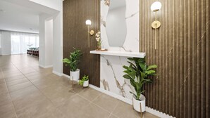 A modern reception area with a marble wall, wooden paneling, and potted plants. - 9BR house sleeps 24 with pool table (Kissimmee)