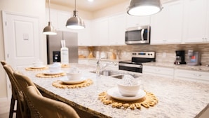 A kitchen with a granite countertop, white cabinets, a microwave, and a coffee maker. - Luxury 5BR Villa - Private Pool - Water Park Resort - Near Disney (Davenport)