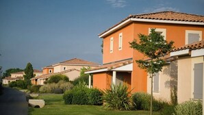 Una hilera de casas anaranjadas con tejados de tejas, rodeadas de céspedes y follaje bien cuidados.