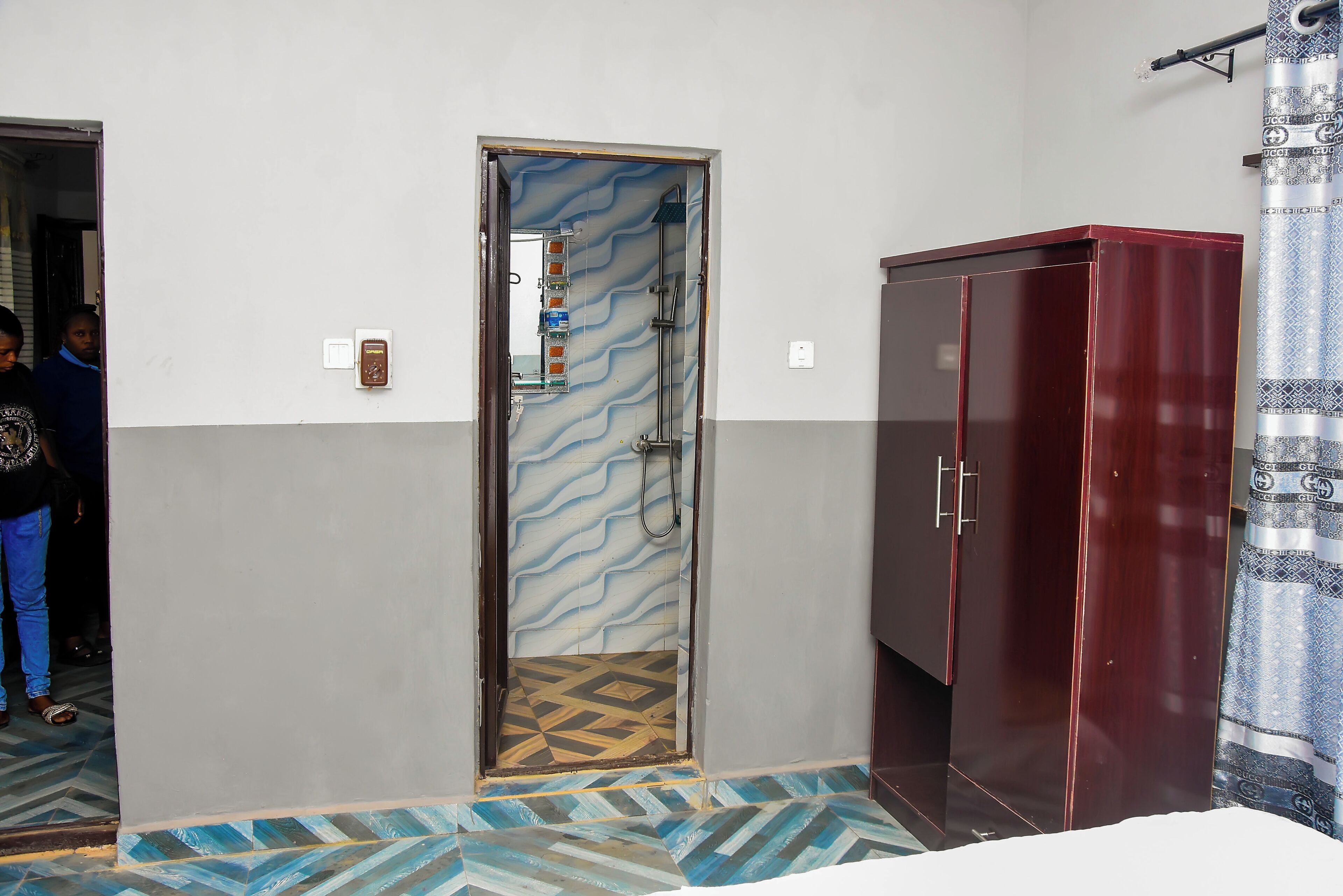 A bathroom with a shower, a vanity, and patterned flooring.