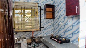 Eine Küche mit Spüle, einem Fenster mit Vorhang, einem Schrank und einem Gasherd.