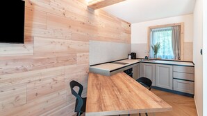 Een moderne keuken met houten kasten, een houten eettafel en een zwarte stoel.