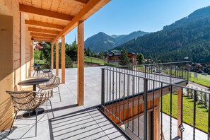 A balcony with a view of mountains, wooden beams, and outdoor furniture. - Noah Suites Neve Apartment with Mountain View, Private Terrace and Wi-Fi (Vigo di Fassa)