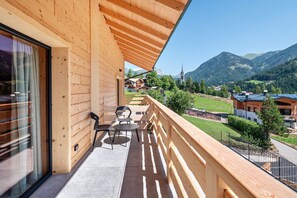 A wooden balcony with a view of a mountain landscape, a church, and a small village. - Noah Suites Piuma Apartment with Mountain View, Shared Garden and Wi-Fi (Vigo di Fassa)