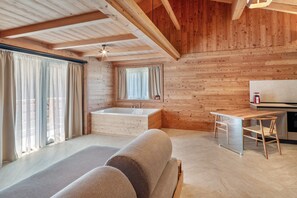 A modern log cabin interior with a large window, a wooden ceiling, a bathtub, and a wooden dining table. - Noah Suites Piuma Apartment with Mountain View, Shared Garden and Wi-Fi (Vigo di Fassa)