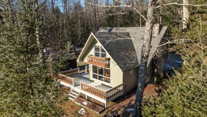 Une cabane dotée d’un balcon, entourée d’arbres.