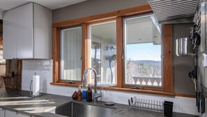 Une cuisine moderne dotée d’une grande fenêtre, d’un évier en acier inoxydable et d’armoires en bois.