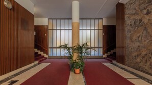 Ein Korridor mit rotem Teppich, Holzwandverkleidung, einer zentralen Säule und einem Blumentopf.
