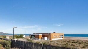 Un edificio frente a la playa con un letrero que dice 'CAPRI sea club' y fachada de madera.