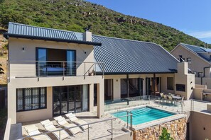 A modern two-story house with a swimming pool, large windows, and a balcony. - Houtbay Hilltop Villa (Cape Town)