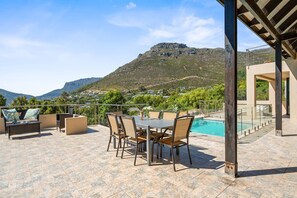 Una terraza con piscina, mobiliario exterior y vistas a la montaña.