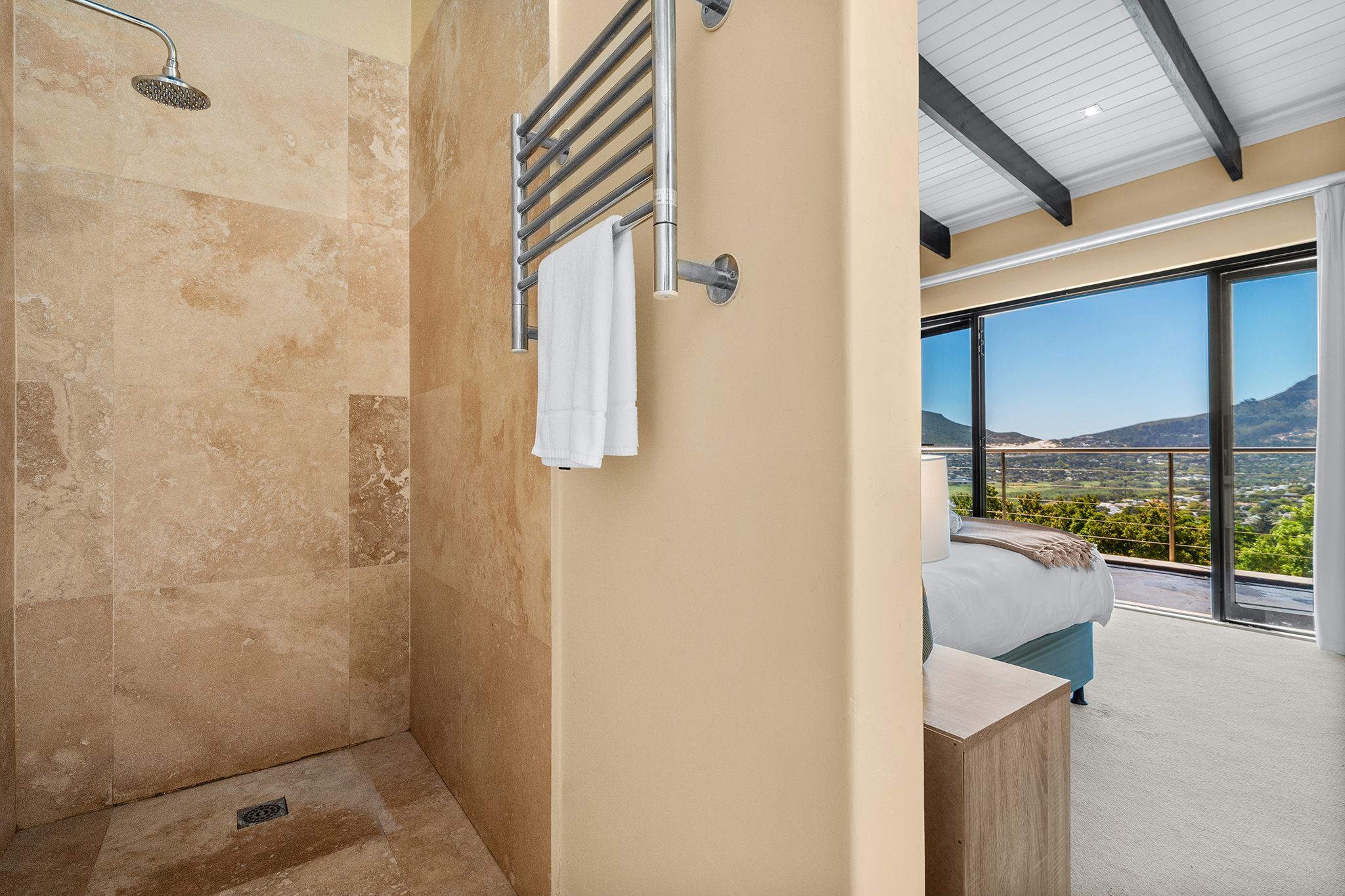 Un baño moderno con ducha, toallero y un amplio ventanal con vistas al paisaje.
