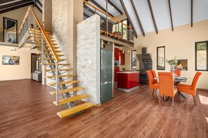 A spacious living area with a wooden staircase, a kitchen with red cabinets, and a dining area with orange chairs. - Houtbay Hilltop Villa (Cape Town)