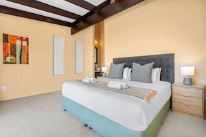 A bedroom with a large bed, a nightstand with a lamp, and a painting on the wall. - Houtbay Hilltop Villa (Cape Town)