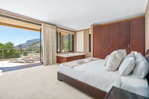 A spacious bedroom with a large bed, a built-in bathtub, and a balcony with a view of the mountains. - Houtbay Hilltop Villa (Cape Town)