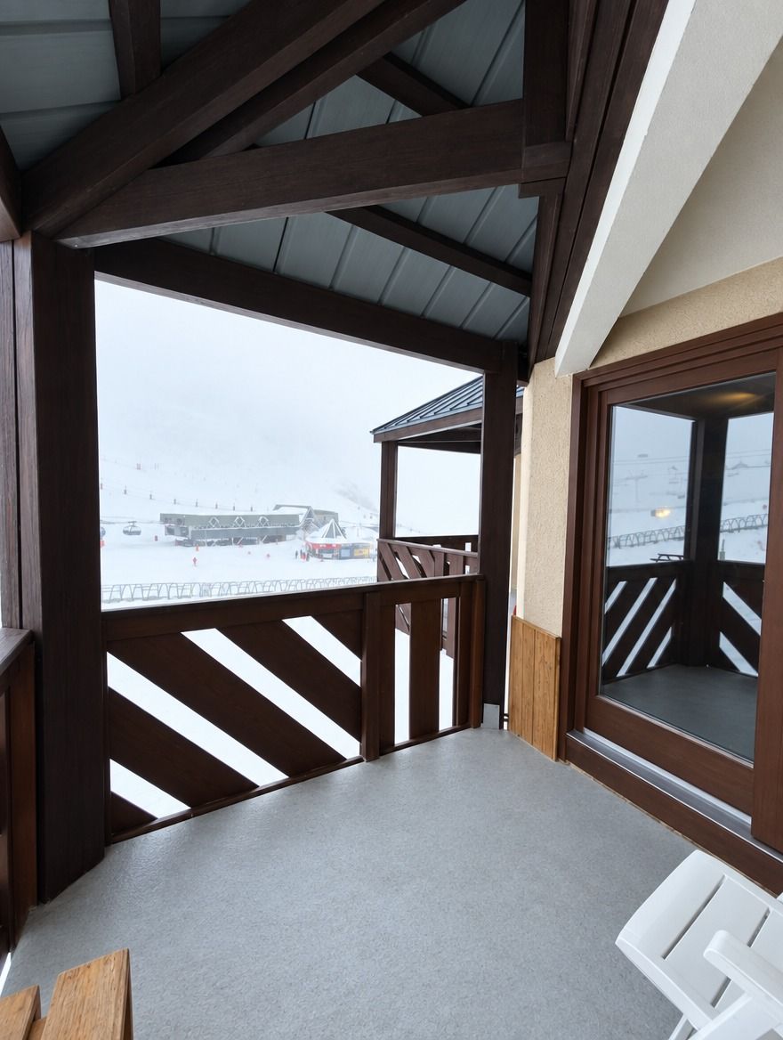 A balcony with a view of a snowy landscape and a building in the distance.