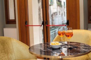 A round table with two glasses of amber liquid and a bowl of chips. - Hotel de l'Alboro (Venice)