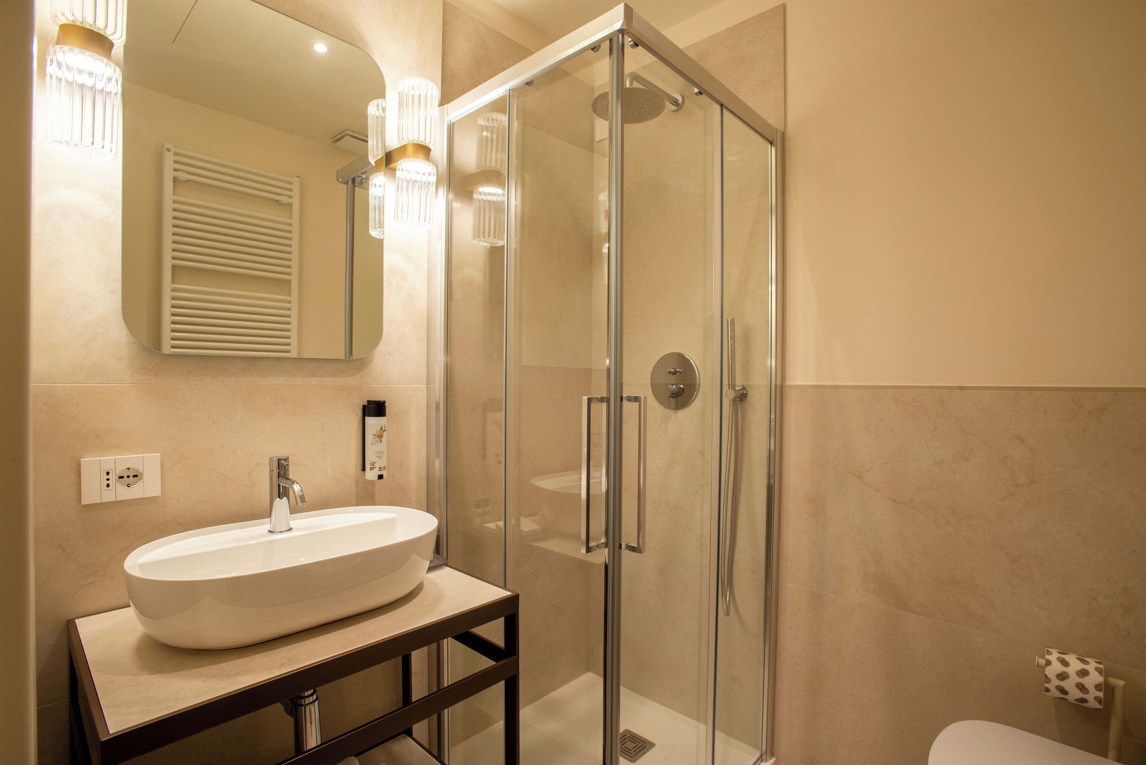 A modern bathroom with a glass-enclosed shower, a white sink on a wooden vanity, and a mirror above the sink.