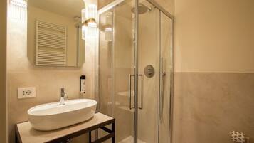 A modern bathroom with a glass-enclosed shower, a white sink on a wooden vanity, and a mirror above the sink.