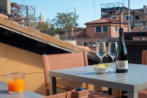 A table with a bottle of wine, glasses, a bowl of chips, and a glass of orange juice. - Hotel de l'Alboro (Venice)