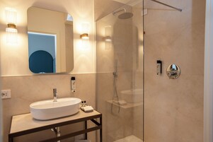 Un baño moderno con ducha envuelta en vidrio, un lavabo blanco e iluminación empotrada.