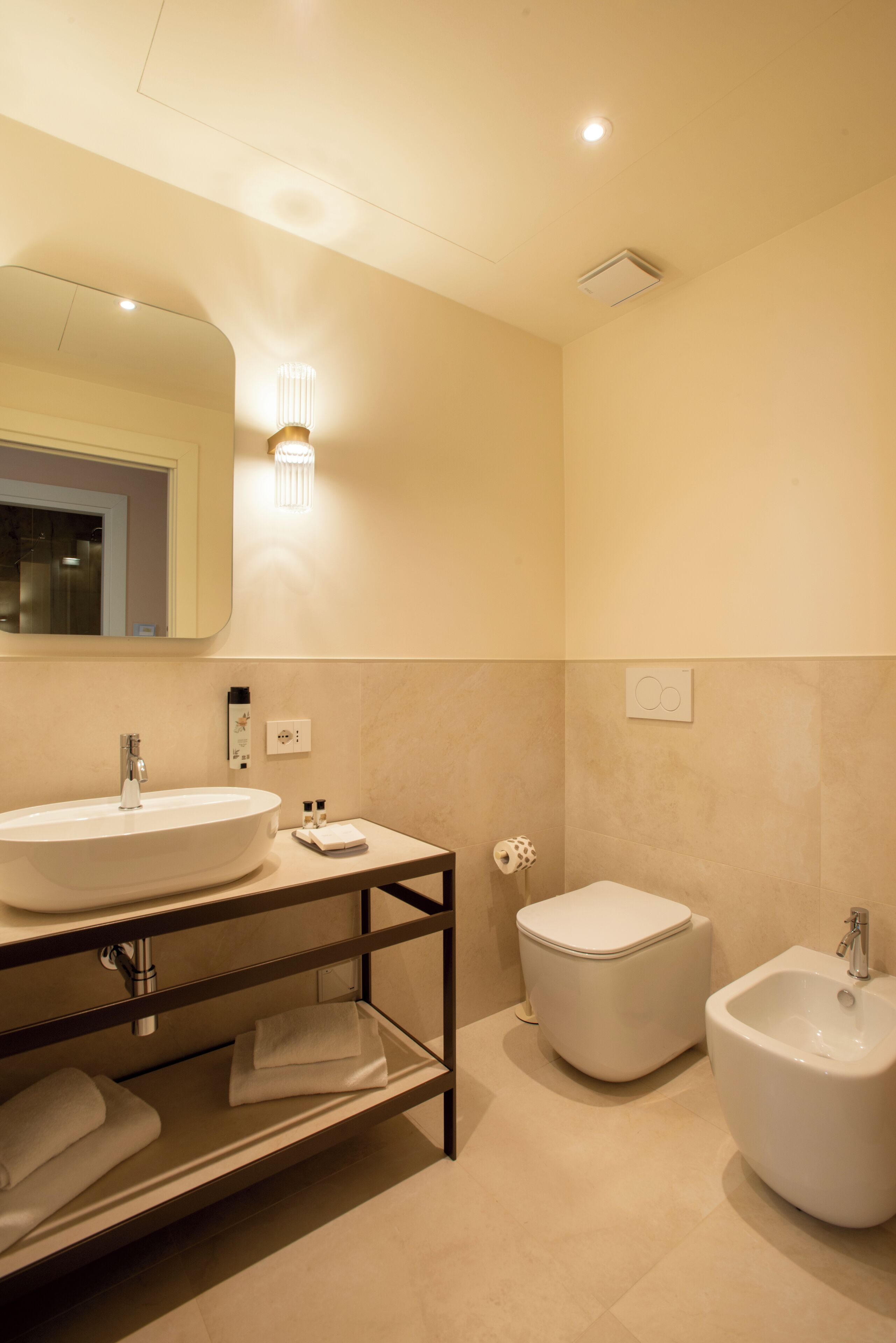 A modern bathroom with a large sink, bidet, and mirror.