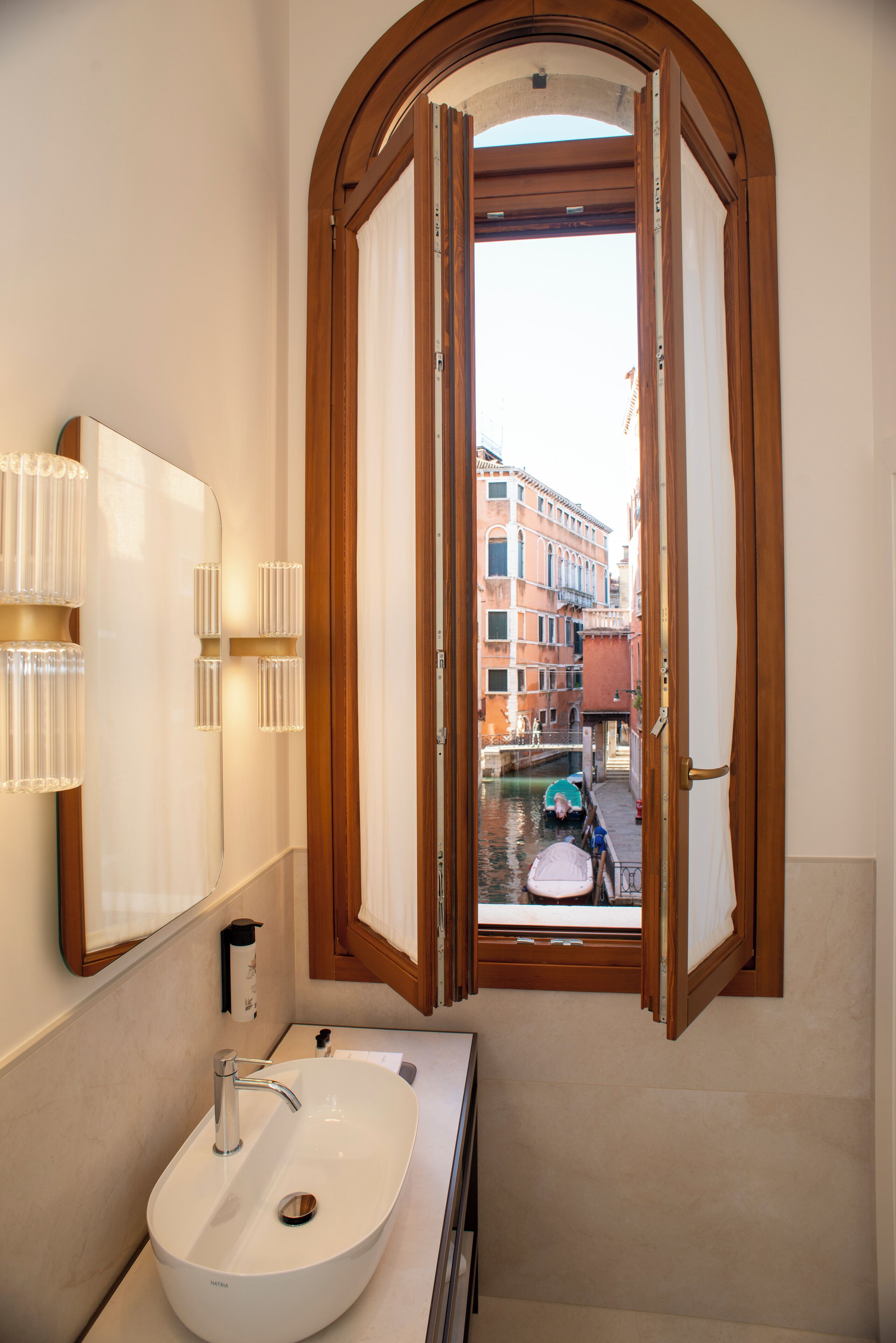 A bathroom with a large window, a sink, and a mirror.