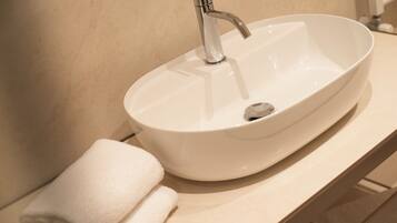 A white ceramic sink with a modern faucet, a towel, and a beige countertop.