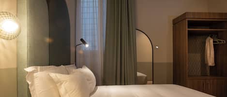 Un lit bien fait, avec des oreillers, une lampe de chevet, une armoire et une fenêtre avec des rideaux.
