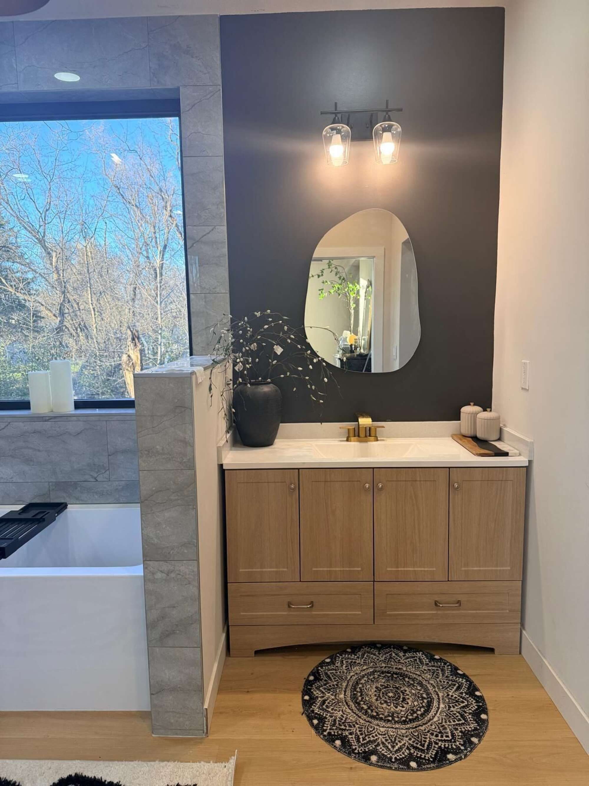 Une salle de bain moderne avec un grand miroir, un lavabo et une baignoire.