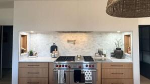Een moderne keuken met een roestvrijstalen fornuis, houten kastjes en een witte achterwand.