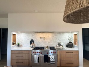 A modern kitchen with a stainless steel stove, wooden cabinets, and a white backsplash. - Vacation home on Alexandria chain of lakes. (Alexandria)