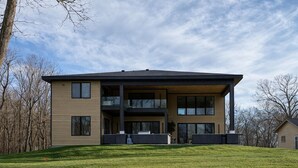 Een modern huis met twee verdiepingen, een plat dak, grote ramen en een overdekte veranda.