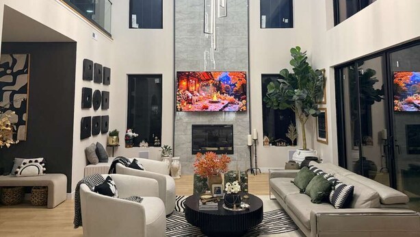 Een moderne woonkamer met een open haard, banken, een salontafel en een tv die aan de muur is bevestigd.