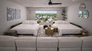 Een moderne slaapkamer met twee bedden, uitzicht op een stadsgezicht en een plafondventilator.