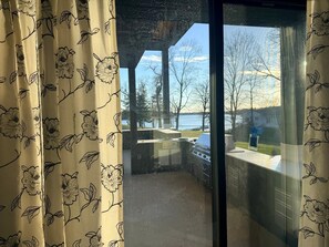 A balcony with a view of a lake and trees, a grill, and a window with a view of a house. - Vacation home on Alexandria chain of lakes. (Alexandria)