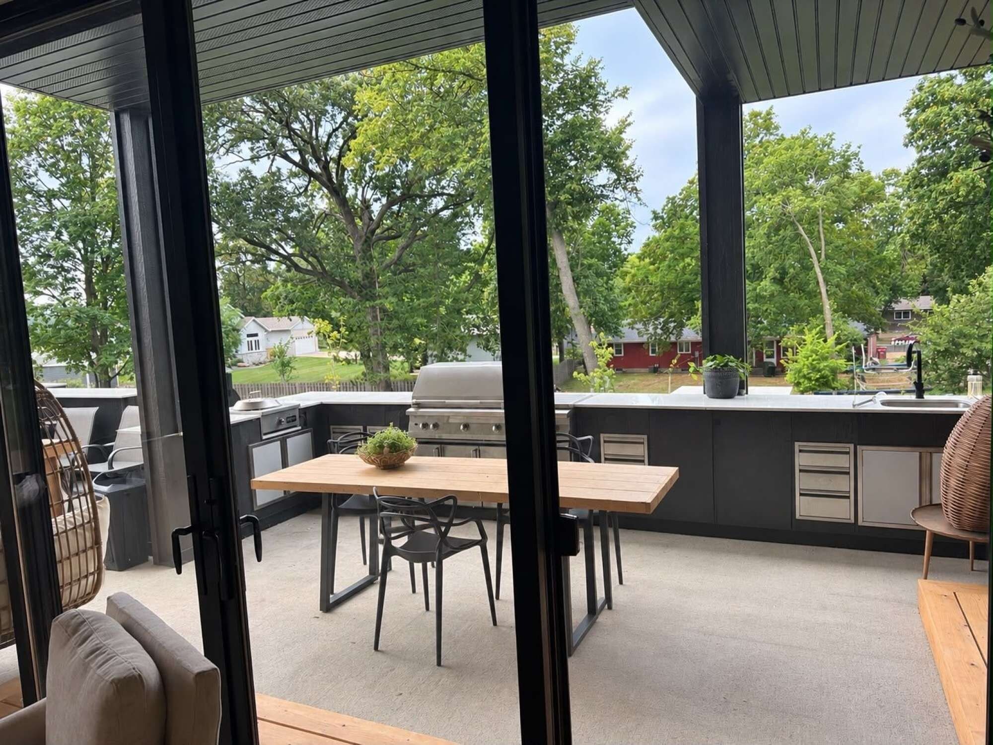 An outdoor kitchen area with a grill, dining table, and chairs.
