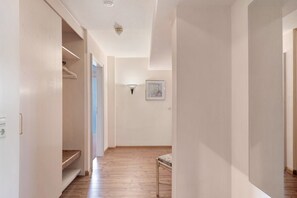 Ein Korridor mit Holzboden, einer Bank, einem Kleiderständer und einer Wandleuchte.