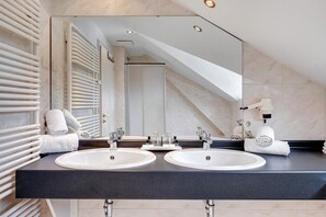 A modern bathroom with two sinks, a large mirror, and a towel rack.