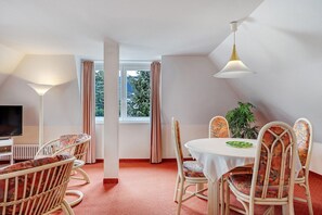 A dining area with wicker chairs, a round table, a television, and a plant. - Apartment '10' with Wi-Fi (Hinterzarten)