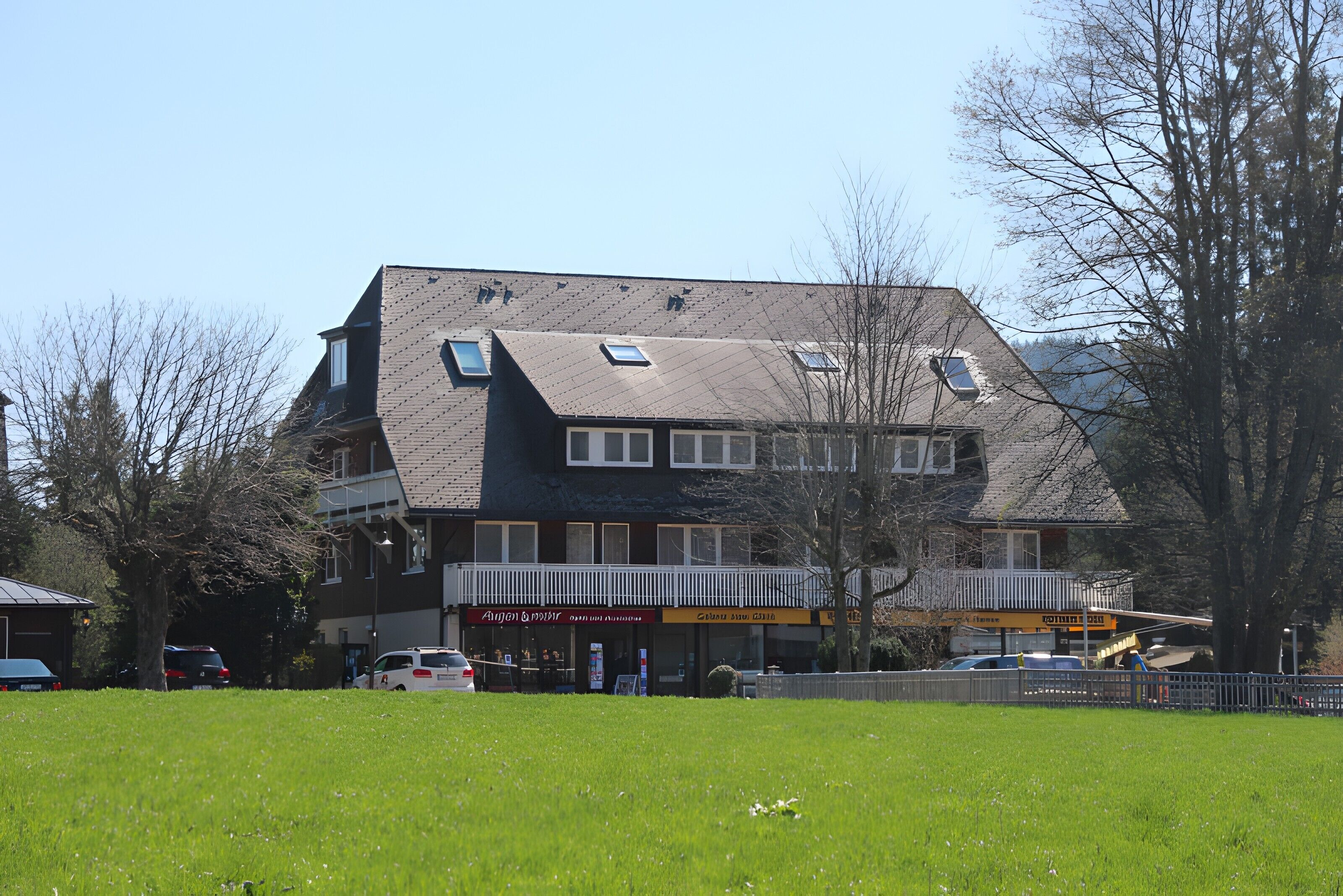 A two-story building with a sloped roof, multiple windows, and a balcony.